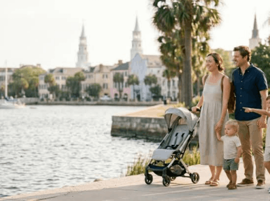 A happy family with a stroller walks along the waterfront battery park while on a trip to visit Charleston SC with kids.
