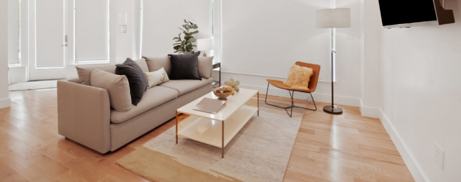 Modern living room interior with a beige sofa, wooden flooring, and large windows with white blinds at The Iris, Premier Suite.