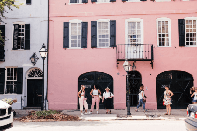 Tourists exploring the historic pastel-colored buildings of Rainbow Row on East Bay Street in Charleston, South Carolina.