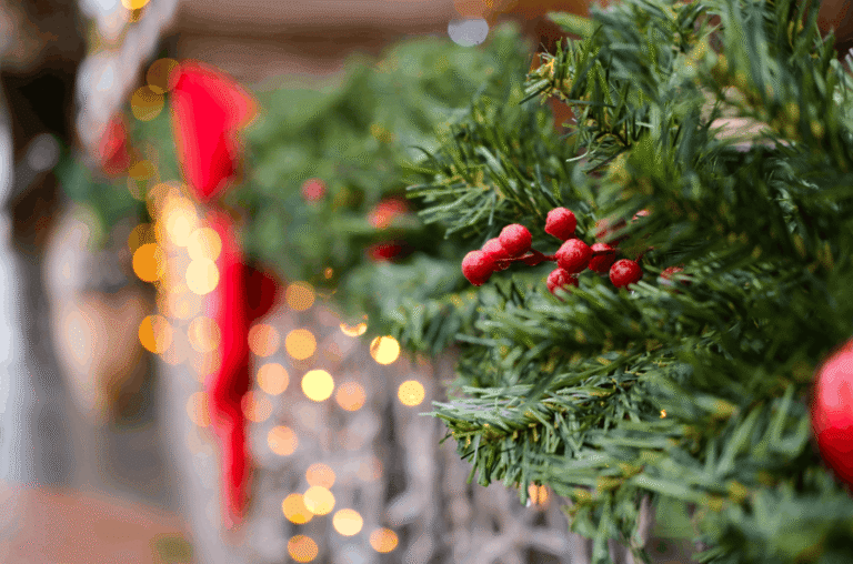 Close-up of a Christmas garland with red berries and glowing bokeh lights for a festive atmosphere