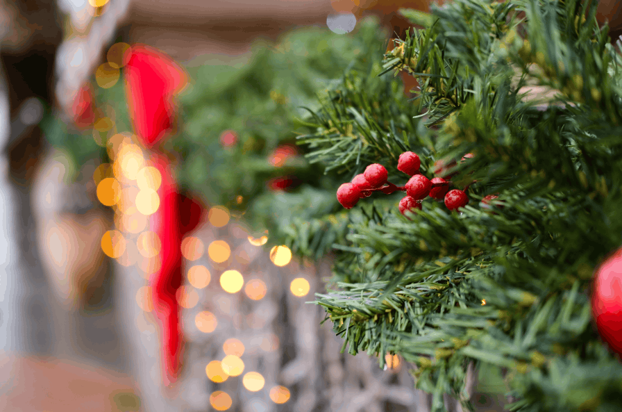 Close-up of a Christmas garland with red berries and glowing bokeh lights for a festive atmosphere