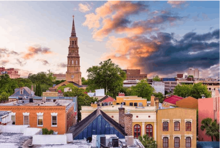 Historic St. Philip's Church steeple rising above the downtown Charleston skyline during a colorful sunset.
