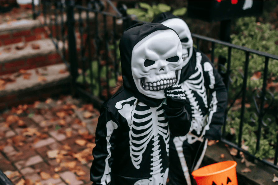 Two children dressed as skeletons trick-or-treating during Halloween.